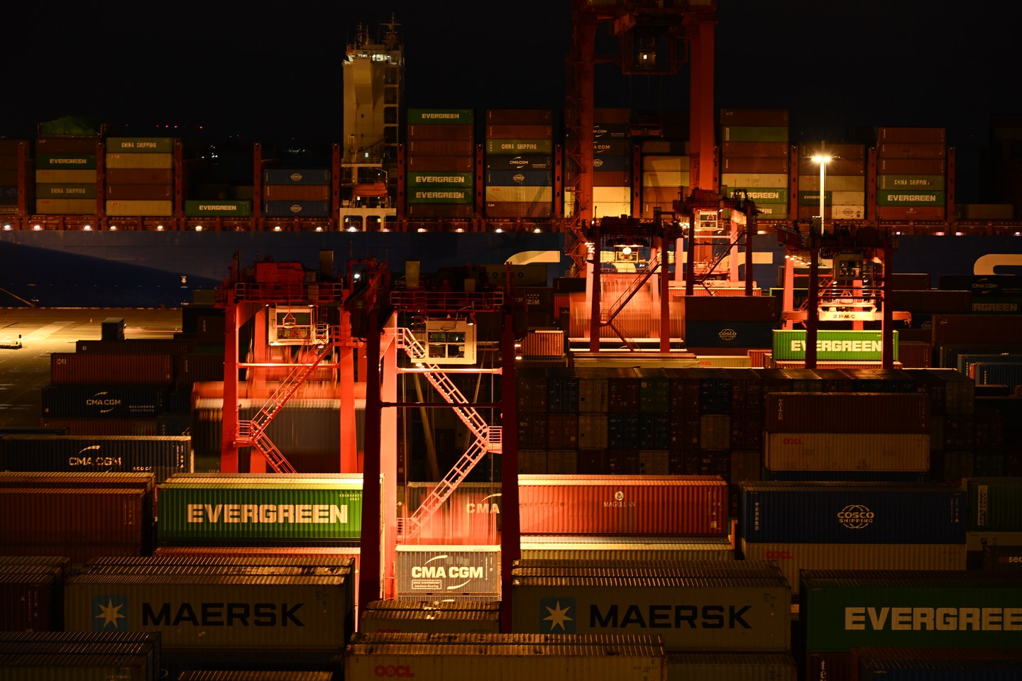 Cranes and stacked shipping containers illuminated after dark at Yangshan Port, Shanghai