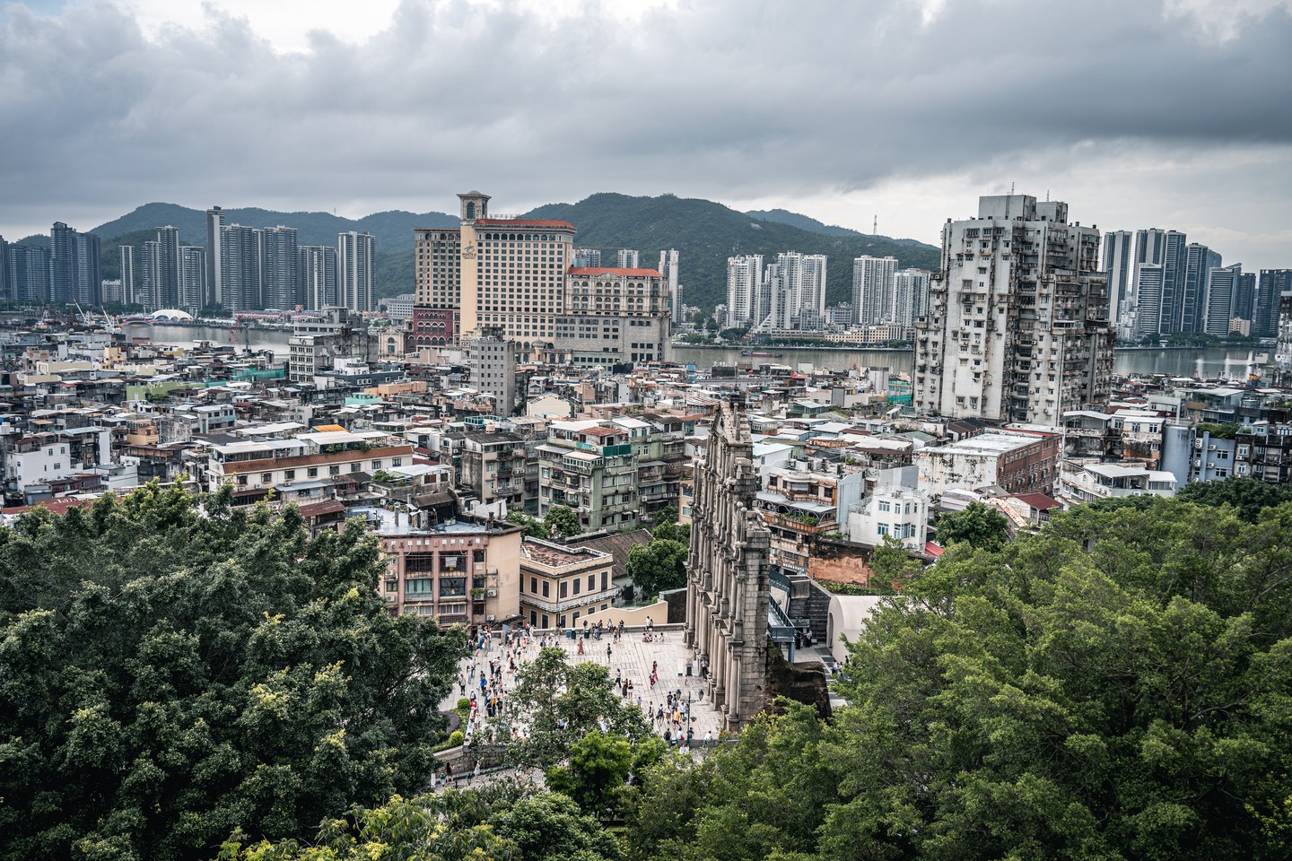 Macau's dense cityscape seen from the Ruins of St. Paul's beneath a cloudy sky