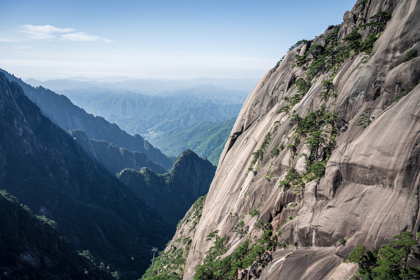 A sheer rock face above layers of distant mountain ridges