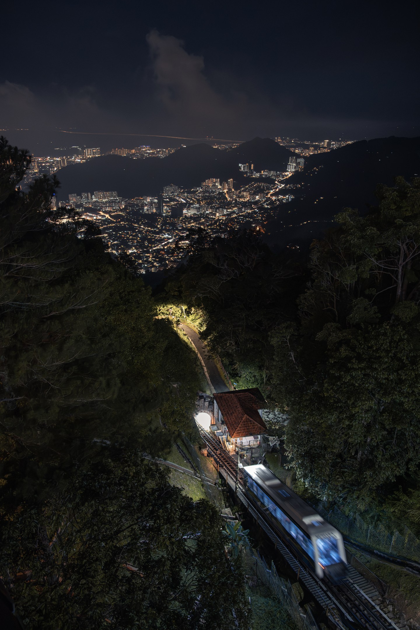 An illuminated railway climbing above a city at night