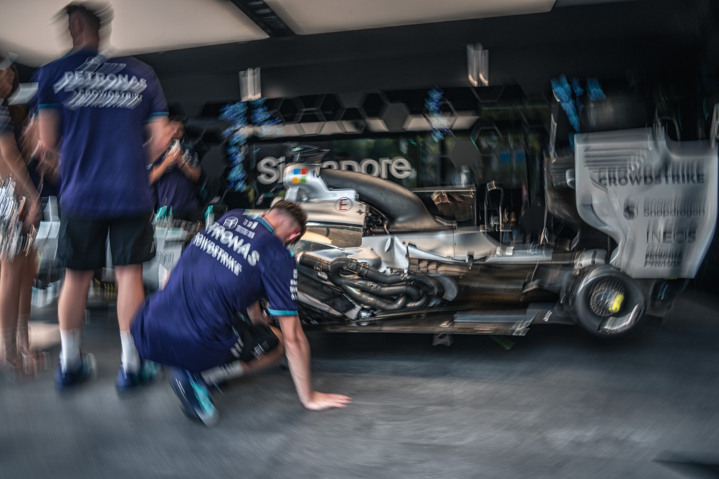 A team member inspecting a silver Formula 1 car