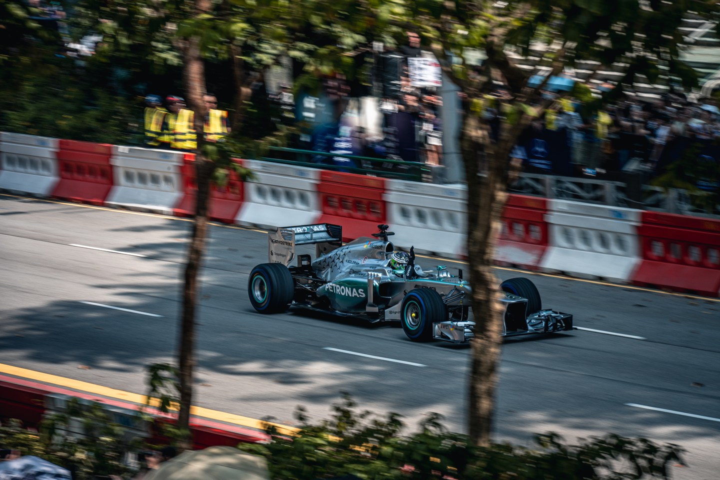 A Mercedes Formula 1 car in motion between roadside trees