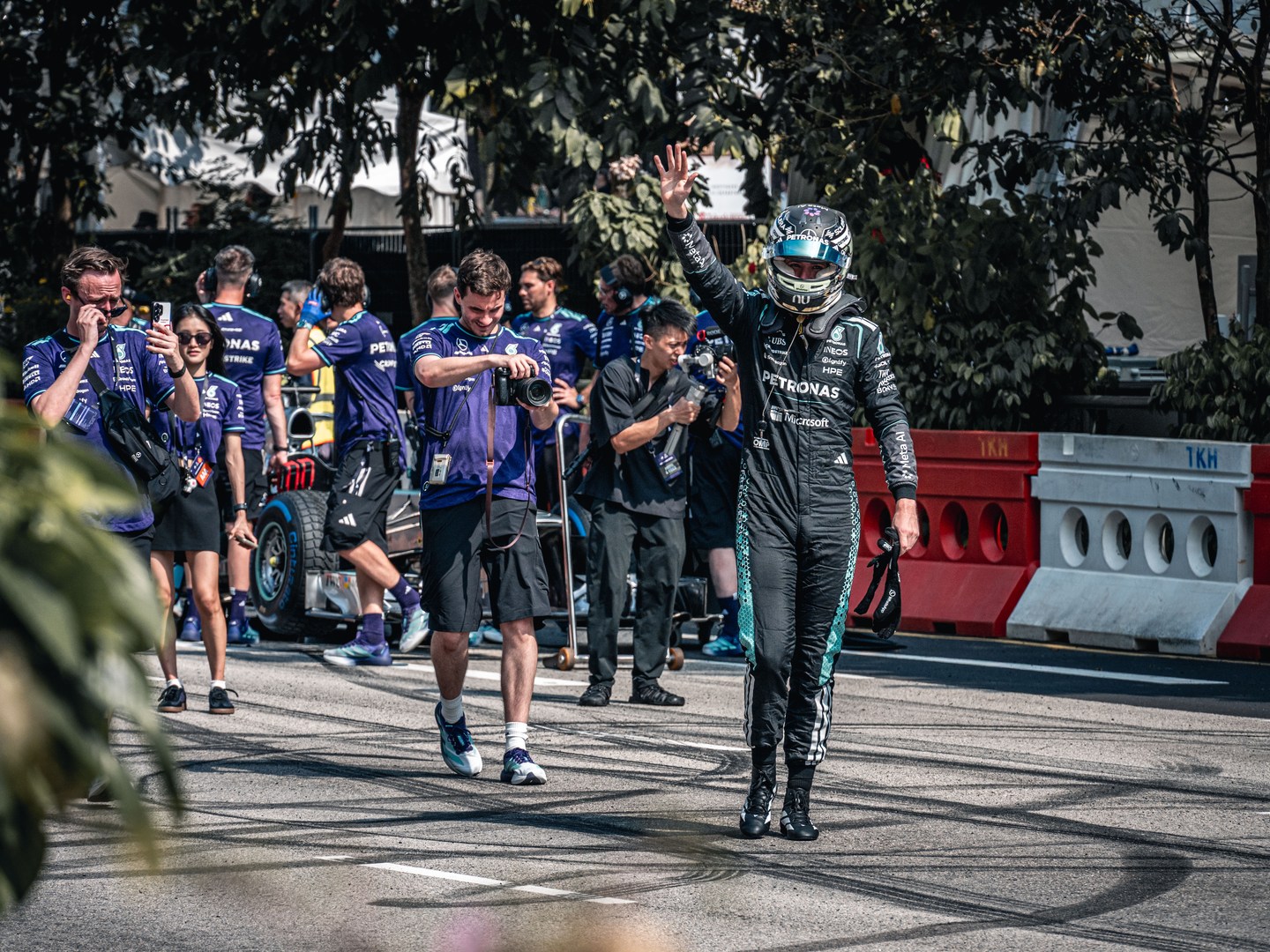 A helmeted driver walking ahead of team members on a city street