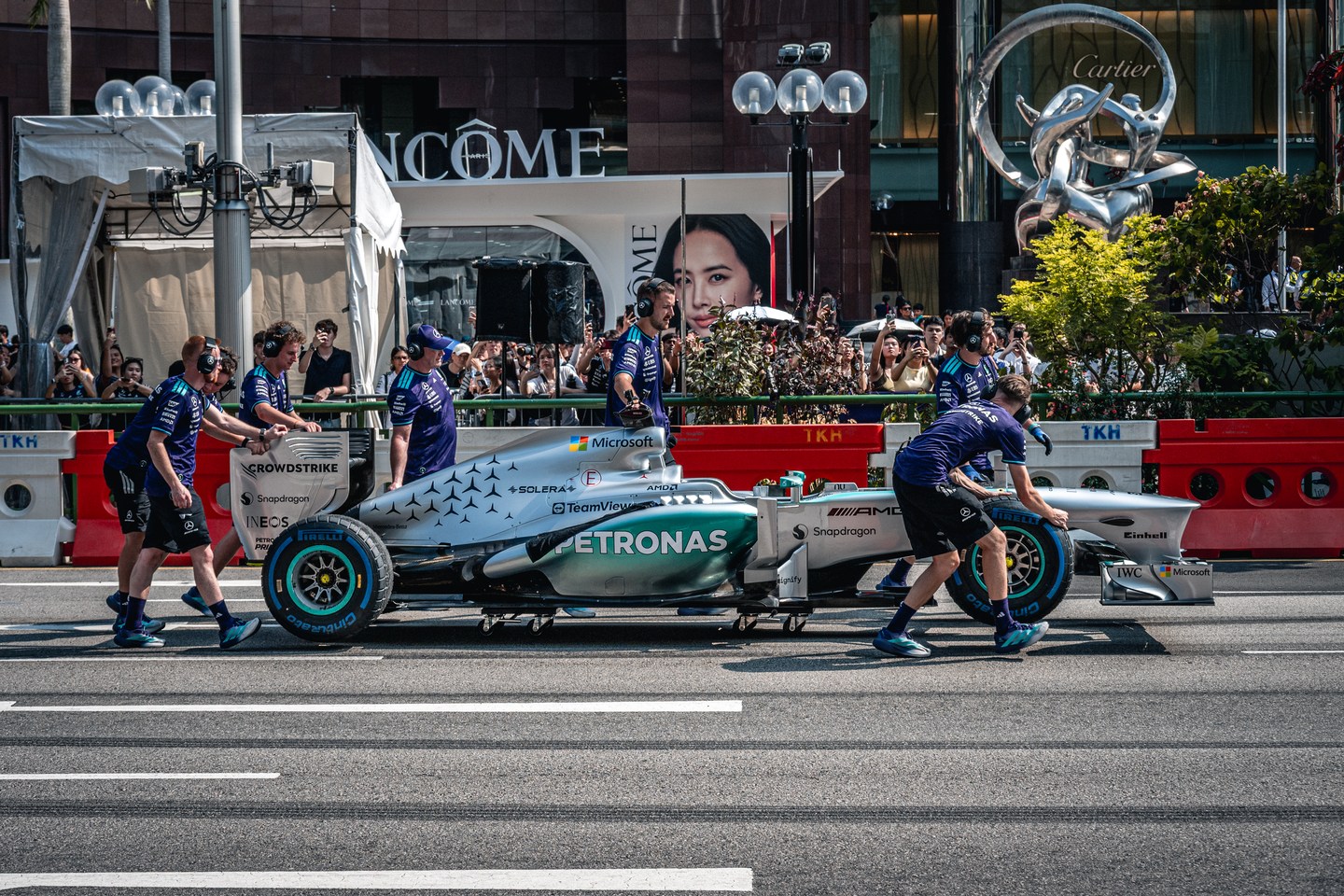 Mercedes team members beside a Formula 1 car at a street event