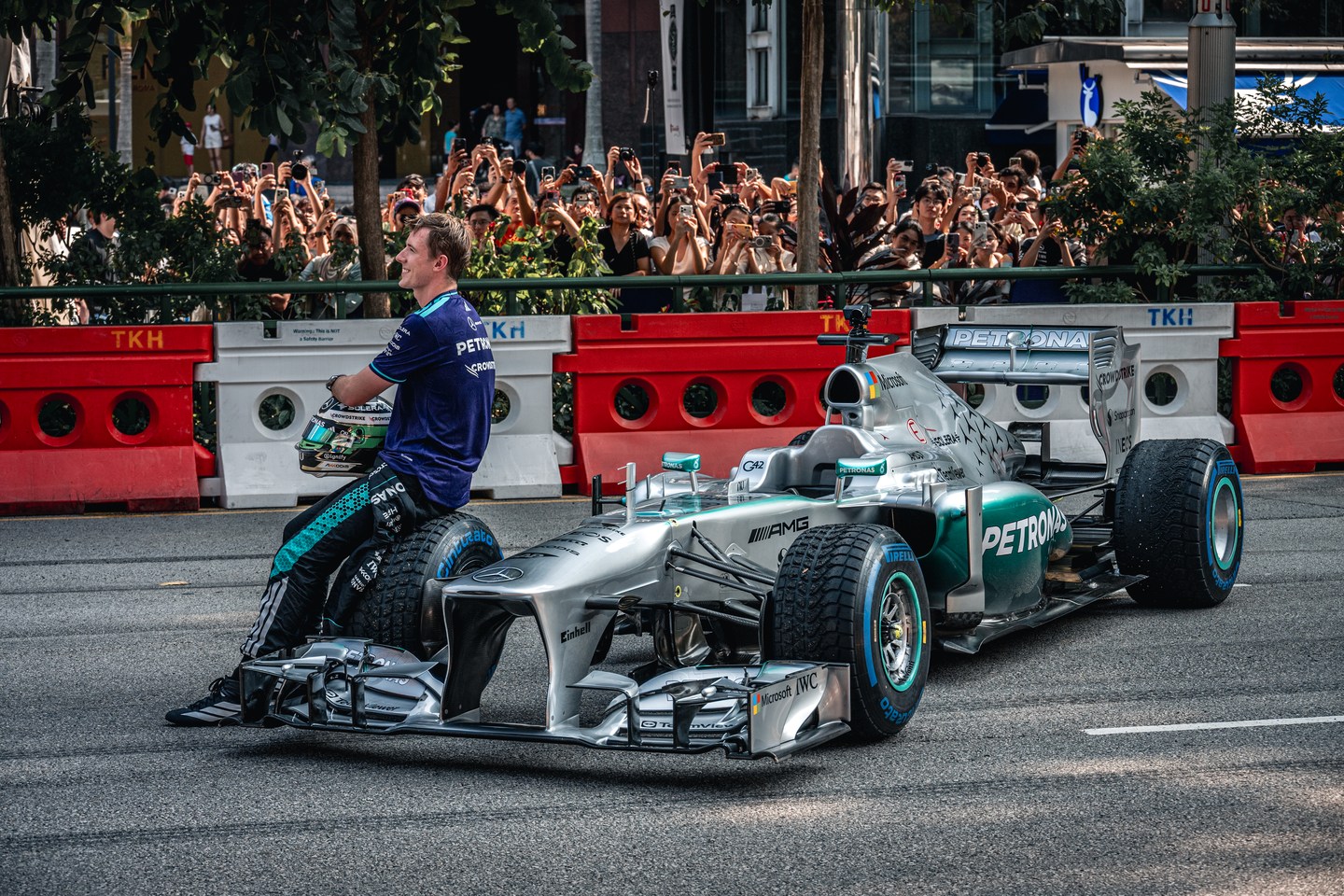 A team member leaning against a silver Formula 1 car