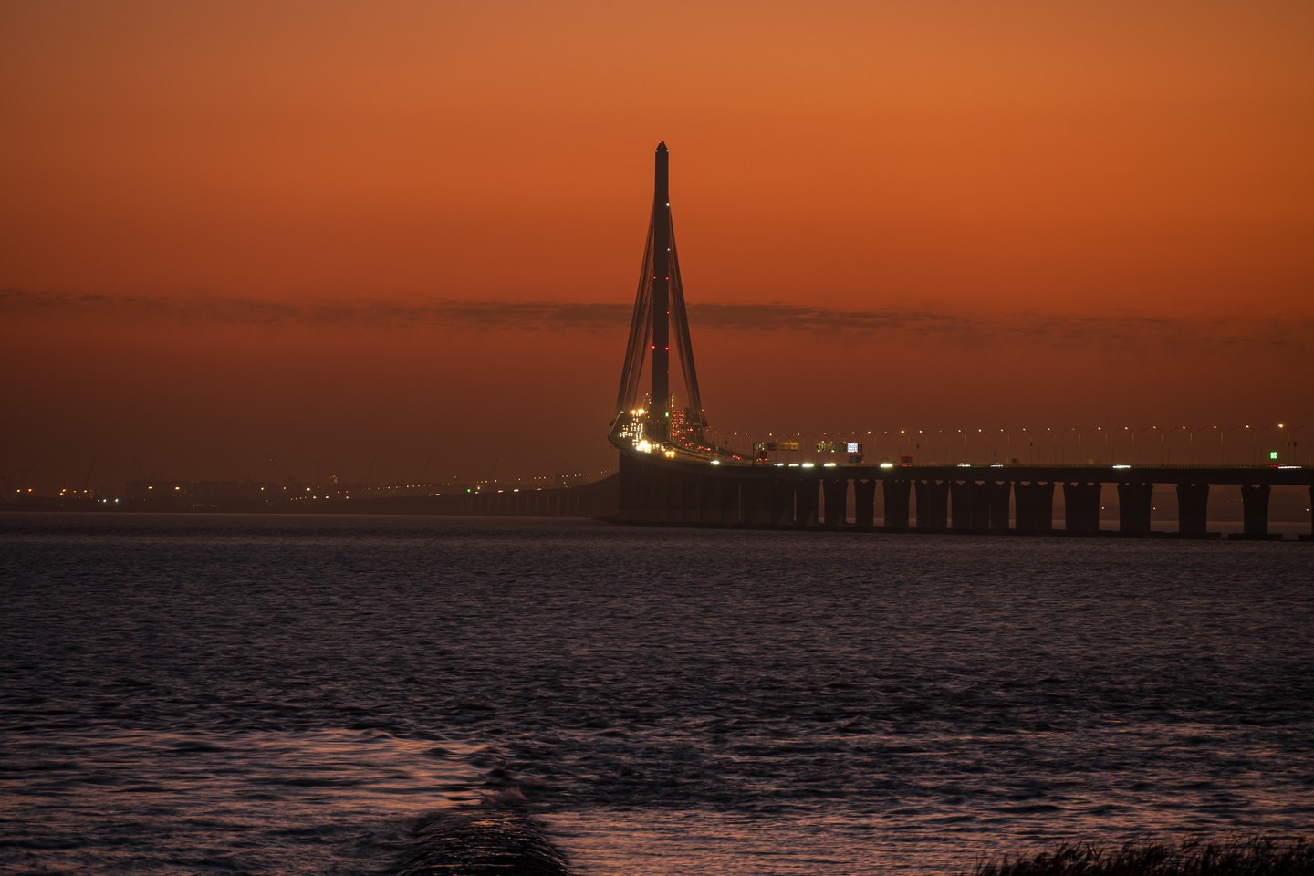 A cable-stayed bridge beneath a deep orange evening sky