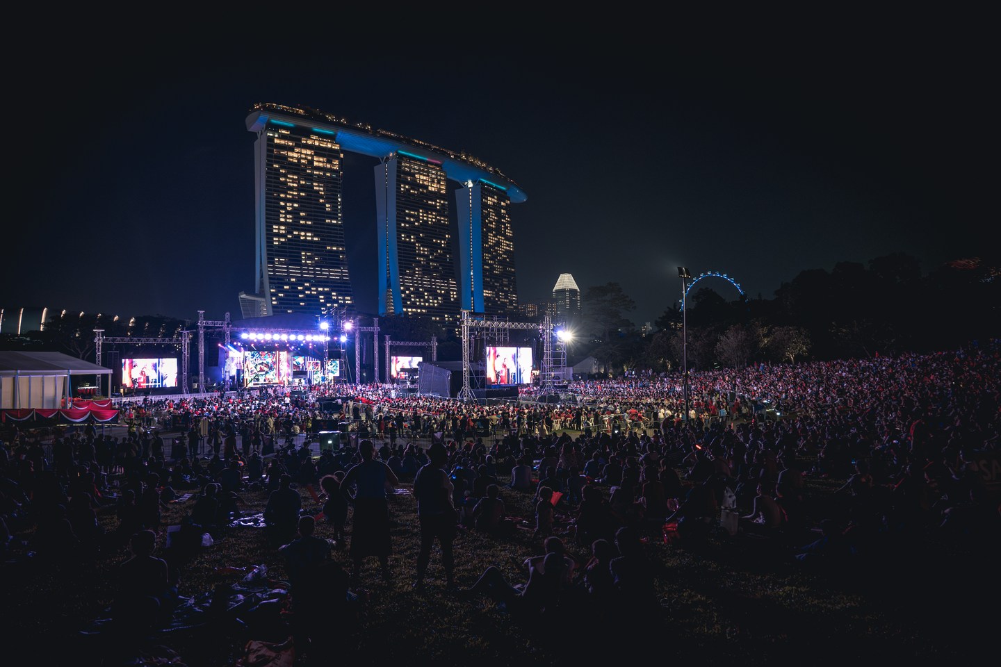 Marina Bay Sands illuminated above a gathering by the water