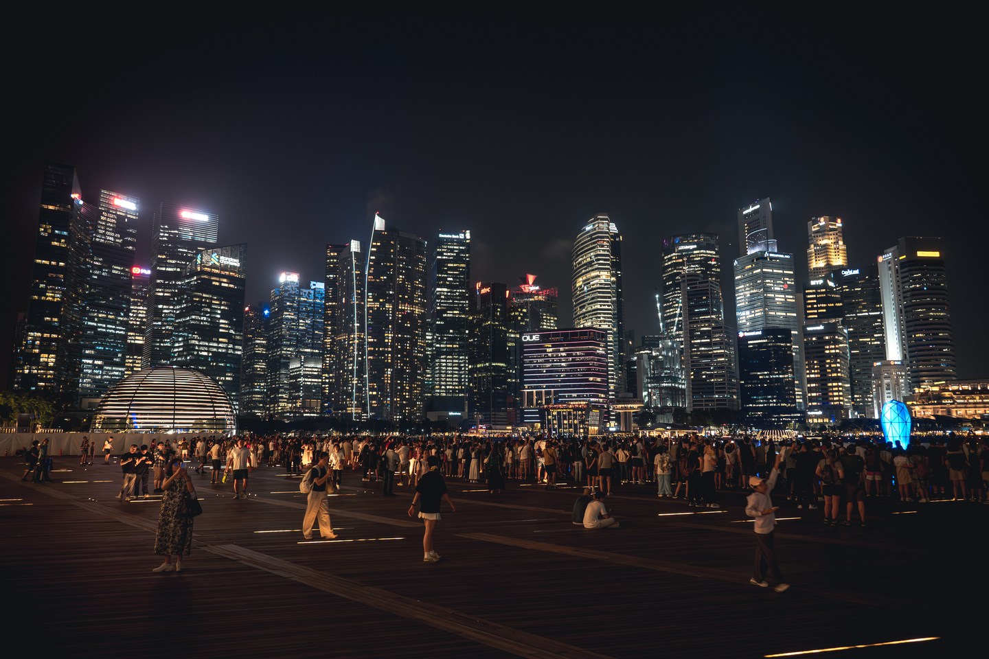Visitors beside the illuminated skyline at Marina Bay