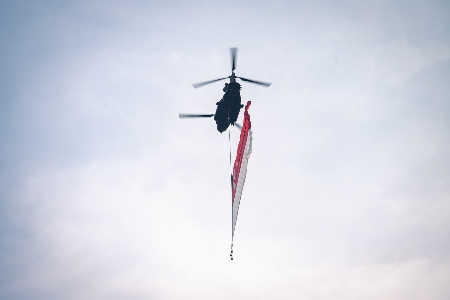 A helicopter carrying the Singapore flag against the sky
