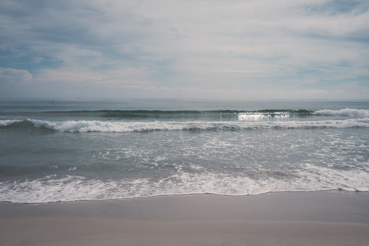Gentle waves reaching an open sandy beach